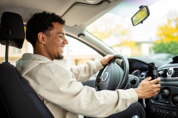 Smiling man driving a car and checking his phone