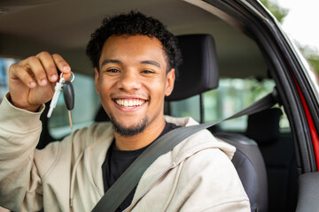 Smiling man holding car keys with seat belt fastened