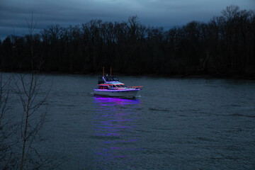 Portland, OR, USA - December 2024 - A scenic view of the illuminated ship parade on the Willamette River, celebrating the 70th anniversary of the event under a dramatic evening sky