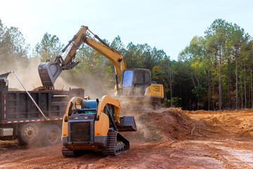 In construction site, earth is loaded into dump truck using an excavator © ungvar