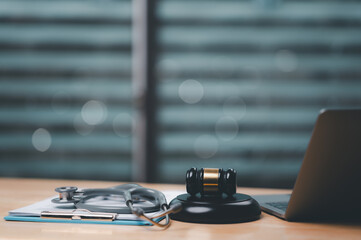 A stethoscope and a gavel are placed on a desk. The gavel is positioned on top of the stethoscope, creating an interesting juxtaposition of two very different objects