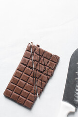 Overhead view of chopped dark chocolate on a white granite countertop, top view of dark chocolate chunks for baking