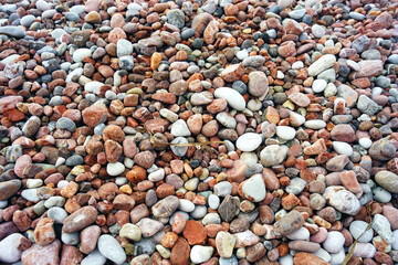 Beaches with beautiful surfaces in Montenegro: a close-up photo of the seashore with colorful pebbles of unusual colors. Pink beach in Sveti Stefan (Budva municipality). Background of colorful stones.