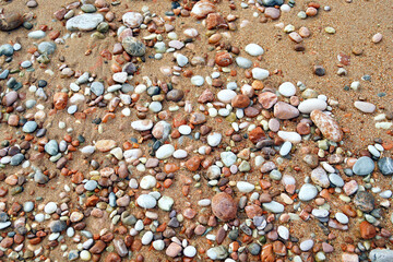 Unusual colorful beach in Montenegro: a close-up photo of the shore with red sand and bright stones of different colors. Walk along the Adriatic coast in Sveti Stefan (Budva municipality).