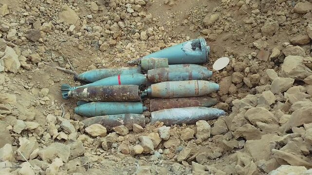 Unexploded shells lie on the ground. Large aerial bombs lie in the crater from the explosion. High quality