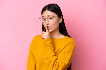 Young Chinese woman isolated on pink background With glasses and doing silence gesture