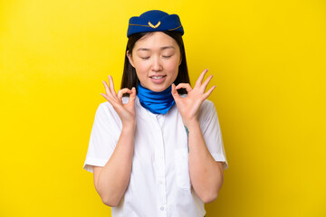 Airplane Chinese woman stewardess isolated on yellow background in zen pose