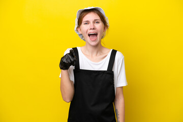 Young English fisherwoman isolated on yellow background surprised and pointing front