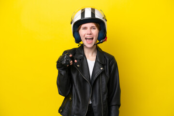 Young English woman with a motorcycle helmet isolated on yellow background surprised and pointing front