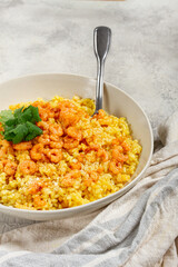 risotto with shrimp, in a bowl, on a textured surface, with a side dish of fresh coriander, homemade, no people,
