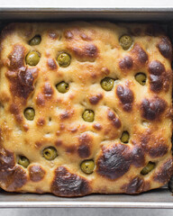 Overhead view of homemade olive focaccia on a white background, Flatlay of focaccia with green olive topping, fresh homemade focaccia bread