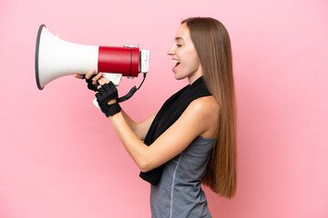 Young sport caucasian woman wearing a towel isolated on pink background shouting through a megaphone