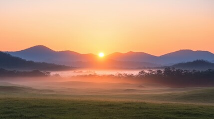 Fototapeta premium A tranquil sunrise over misty hills and valleys, casting warm light across a peaceful landscape.