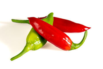 Three freshly harvested red and green chili peppers displayed o a white surface
