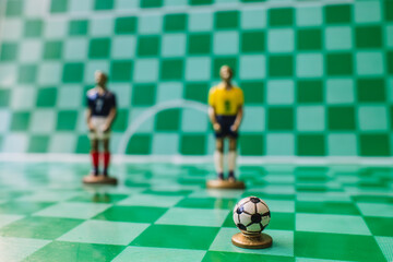 Soccer strategy concept with miniature referee and players on checkered field, tactical game setup