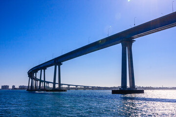 Fototapeta premium A large bridge spans a body of water, with a clear blue sky above