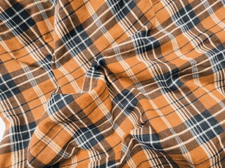 The pattern and background of the fabric has a orange checkered motif