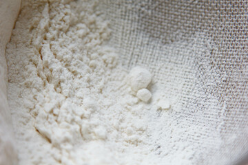 Flour in a stylish dish, prepared for further cooking. There is a stained sieve surrounded by flour.