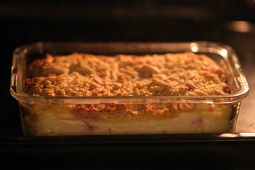 Baked homemade cake in glass casserole dish inside oven. Freshly baked dessert with golden crust. Kitchen cooking concept for food preparation and baking photography.