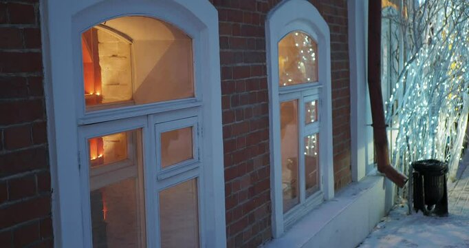 Christmas decorations. The branches of the tree placed next to the glowing windows are beautifully decorated with bright garlands. Hend held. Siberia.