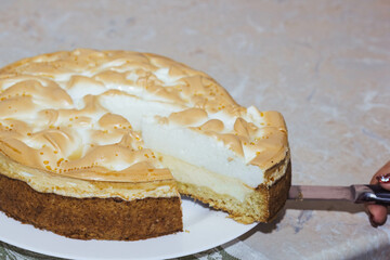 A portion of a delicious bright orange pumpkin open pie on a plate cut from a whole cake, toasted with cream, on a napkin, close-up, top view.