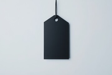 Simple black tag hanging against light background showcasing minimalistic design and empty space for customization