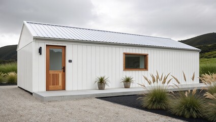 minimalist, single-story building with a modern architectural style. The structure features a white exterior with a corrugated metal roof. 