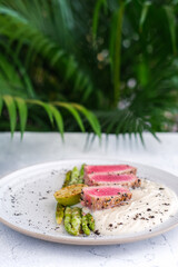 A gourmet dish featuring seared tuna slices, grilled lime, asparagus, and creamy puree