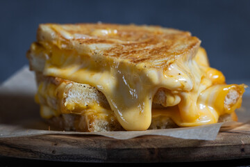 Grilled Cheese with melting cheese dripping from the inside. The sandwich is cut in half and placed...