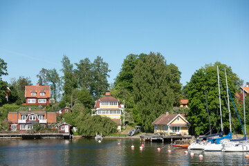 Fototapeta premium Typical Swedish red and yellow wooden houses with white trims by sea shore in idyllic summer landscape in Stockholm archipelago