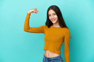 Young French woman isolated on blue background doing strong gesture
