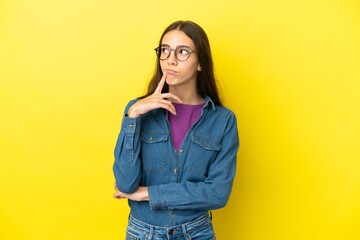 Young French woman isolated on yellow background having doubts while looking up