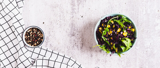 Vegetarian salad of purple cabbage, corn and arugula in a bowl top view web banner