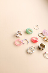 Stylish feminine golden and silver rings on beige background. Top view. flatlay