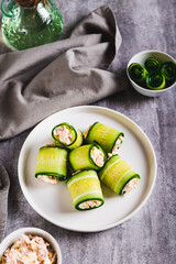 Cucumber rolls with fish salad on a plate on the table vertical view