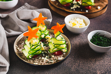 Christmas trees made of cucumber and cherry tomatoes on skewers on a plate on a table