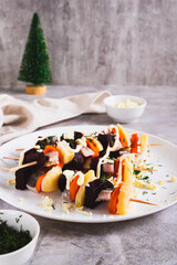 Unusual herring under a fur coat on skewers on the table vertical view