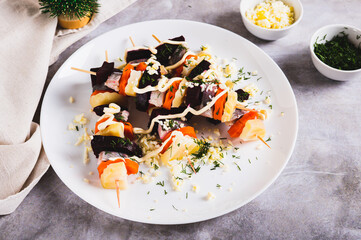 Christmas salad herring under a fur coat on skewers on a plate on the table