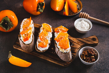 Sweet bruschetta with persimmon and ricotta on a board on a table