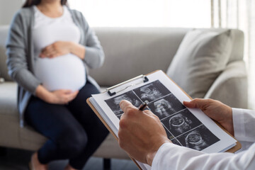 Gynecologist looks at an ultrasound of a pregnant woman. Prenatal health care.
