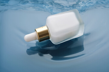 Bottle with white moisturizing serum in water on blue background.