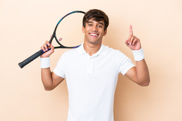 Young caucasian man isolated on ocher background playing tennis and pointing up