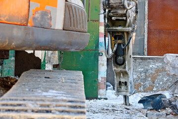 Excavator with mounted hydraulic hammer. Demolishing an old building, powerful hydraulic machinery and heavy equipment operations. Hydraulic hammer to break down an old structure at construction site