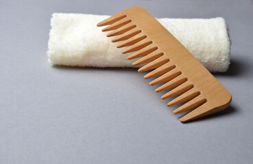 Wooden comb close-up, on a beige napkin on a neutral gray background.