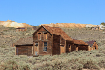 A small house with a slanted roof sits in a field