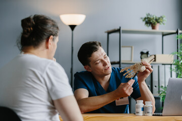 Physician explaining treatment details using a foot skeleton model in a doctor's office.