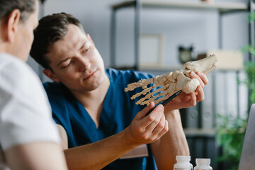 Physician explaining treatment details using a foot skeleton model in a doctor's office.