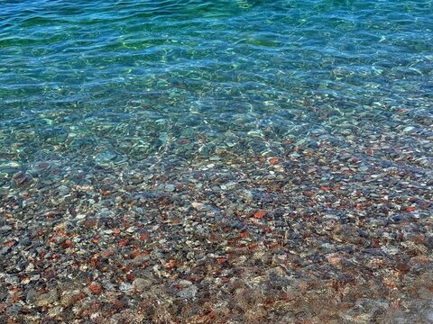 Blue sea clear waves on pebble beach.
