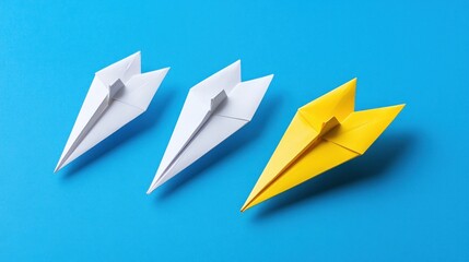Three paper airplanes; two white, one yellow, on blue background.