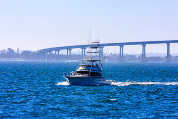 A boat is sailing in the ocean with a bridge in the background